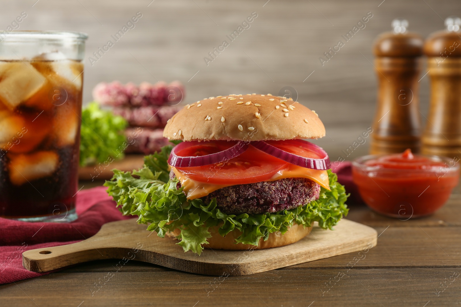 Photo of Tasty vegetarian burger with beet patty, sauce and soda drink on wooden table