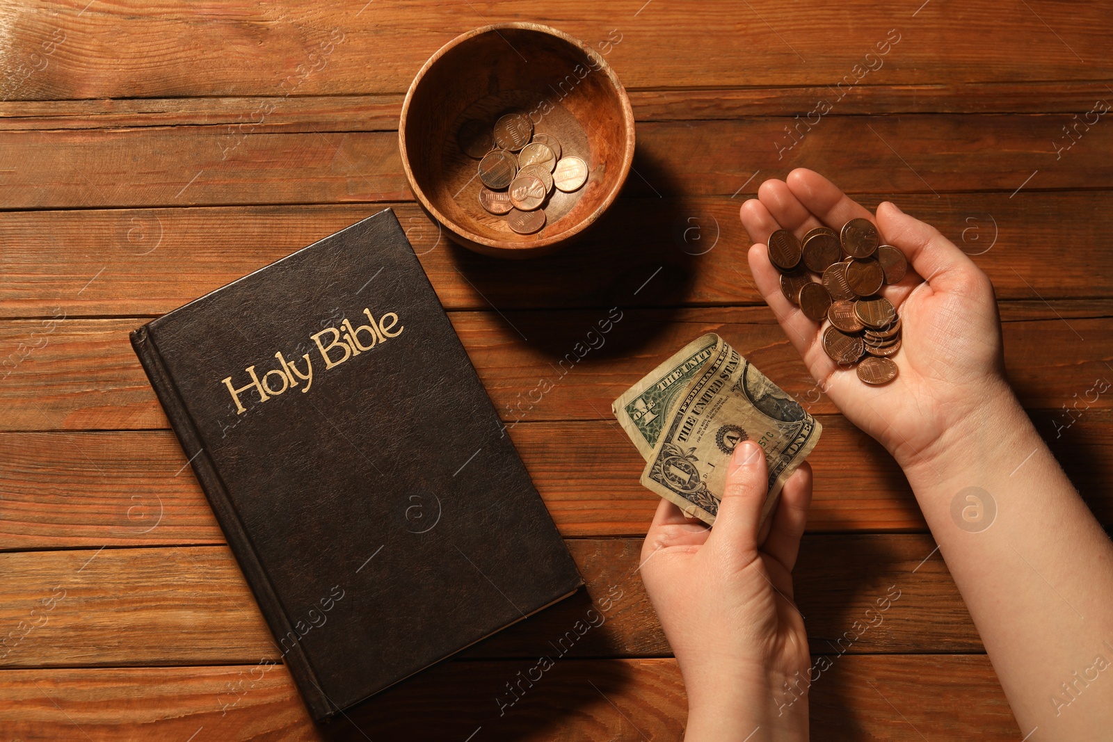 Photo of Donate and give concept. Woman with money, closeup. Bible and bowl of coins on wooden table, top view
