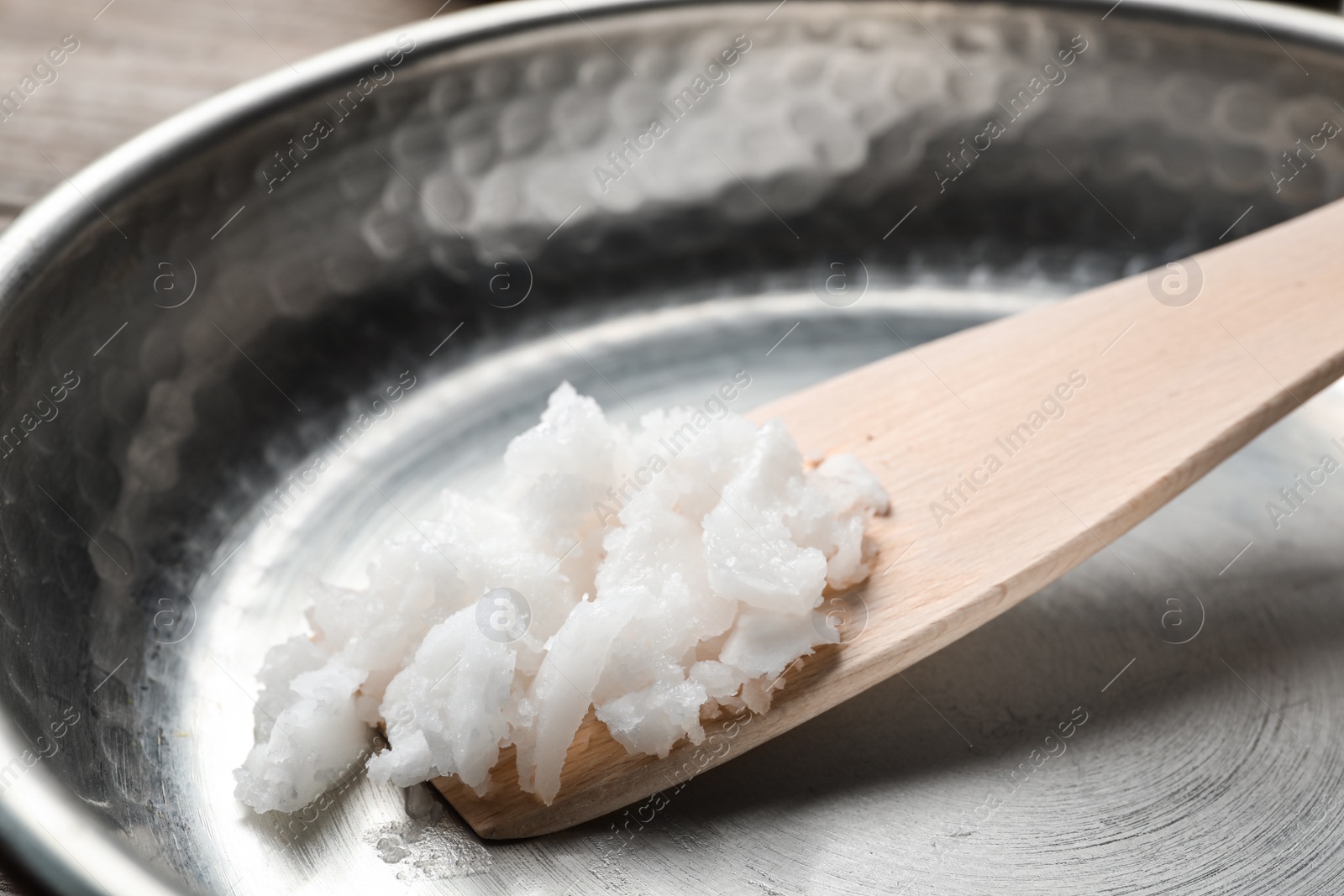 Photo of Frying pan with coconut oil and wooden spatula, closeup. Healthy cooking