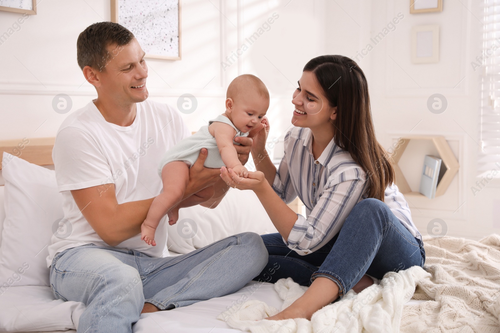 Photo of Happy family with their cute baby on bed at home