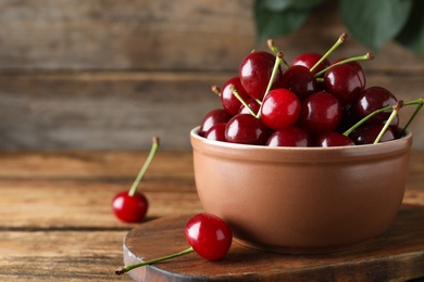 Photo of Sweet juicy cherries on wooden table. Space for text