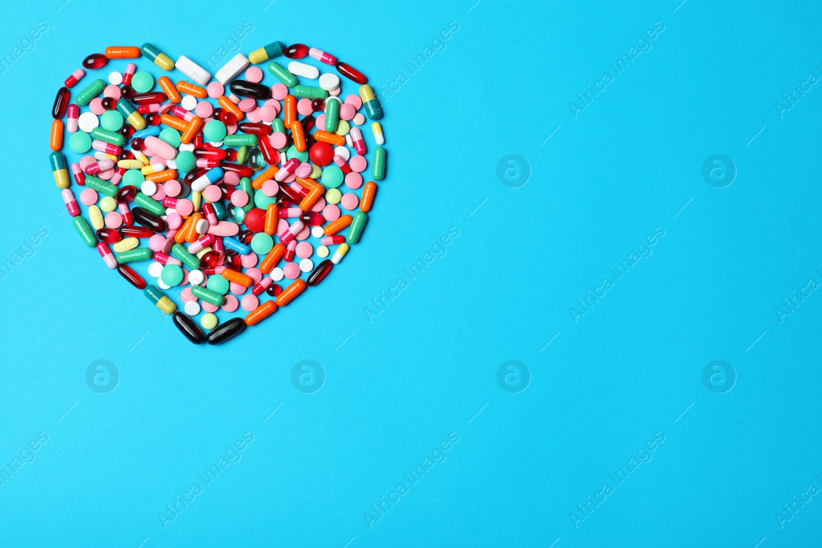 Photo of Heart made of pills on color background, top view. Space for text