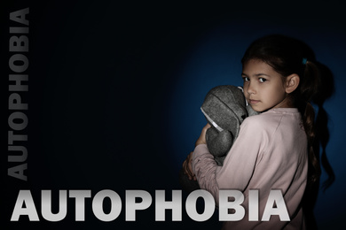 Image of Sad little girl with toy near blue wall. Autophobia - fear of isolation