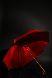 Photo of Open stylish red umbrella on black background