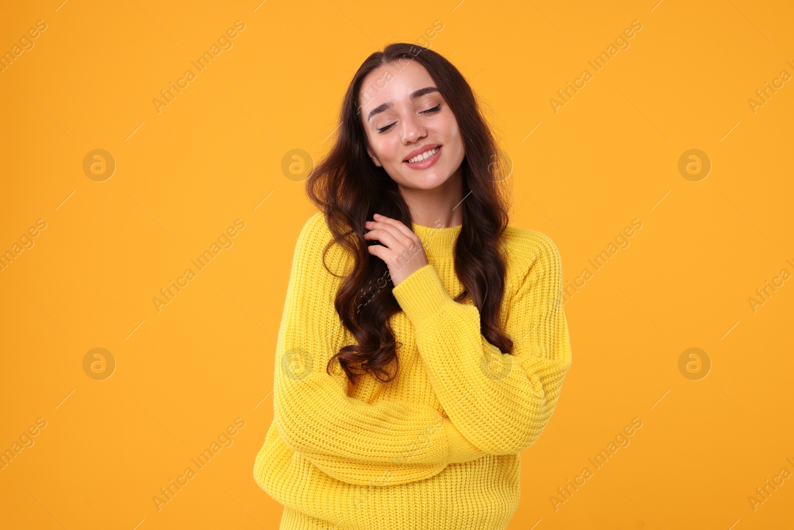 Photo of Beautiful young woman in stylish warm sweater on orange background