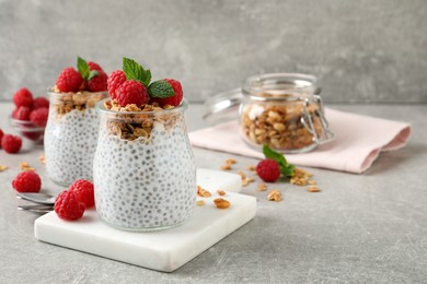 Delicious chia pudding with raspberries and granola on grey table. Space for text