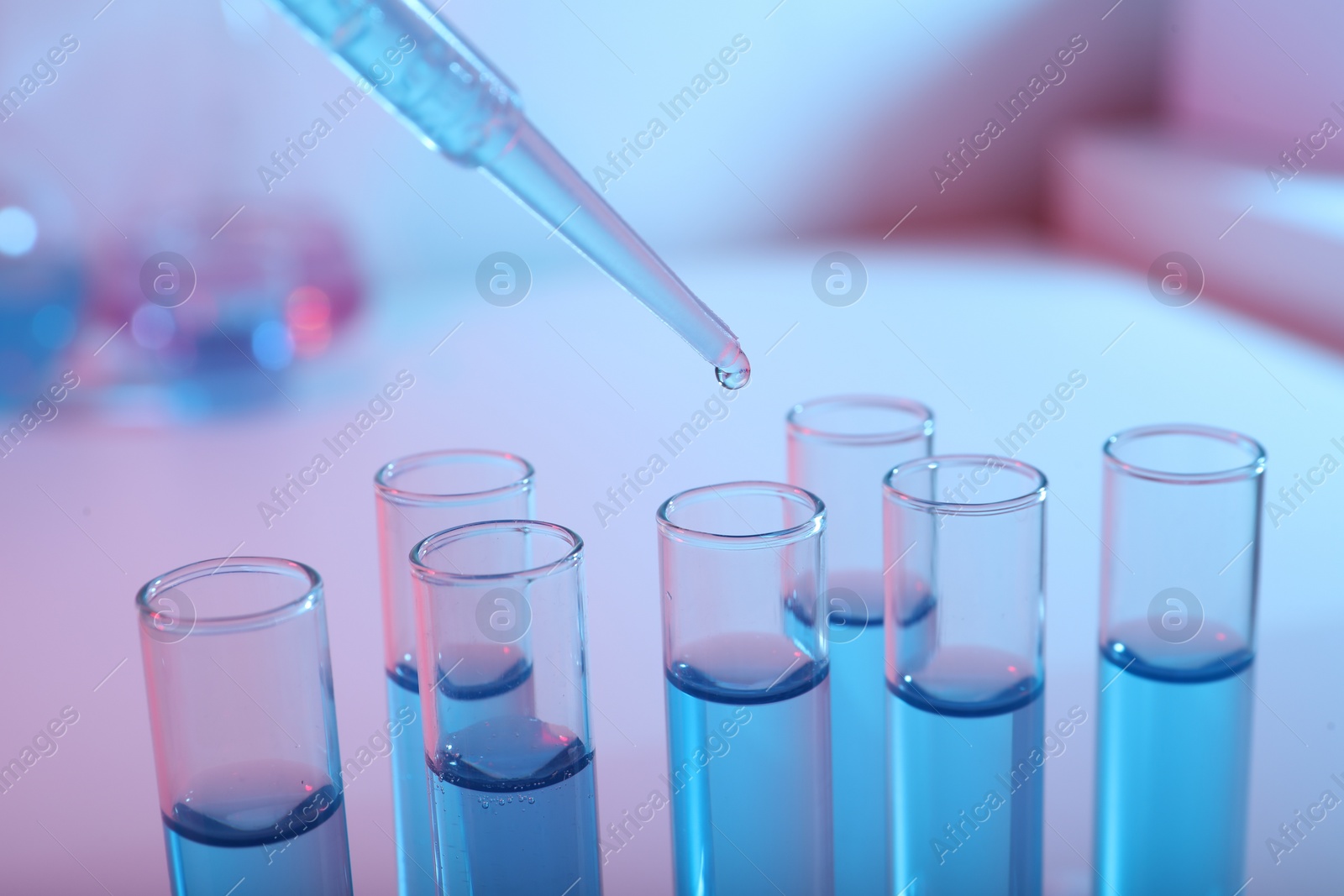 Photo of Dripping reagent into test tube with blue liquid, closeup. Laboratory analysis