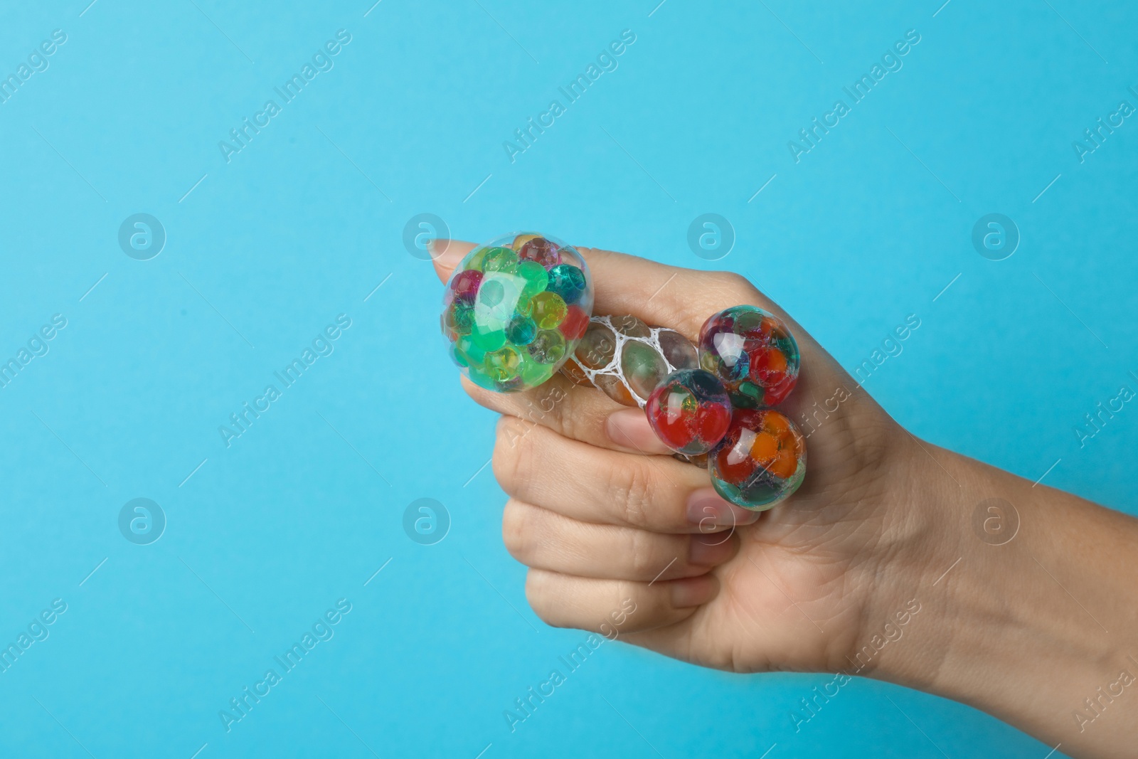 Photo of Woman squeezing colorful slime on blue background, closeup. Antistress toy