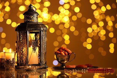 Arabic lantern, burning candles, dates and misbaha on mirror surface against blurred lights