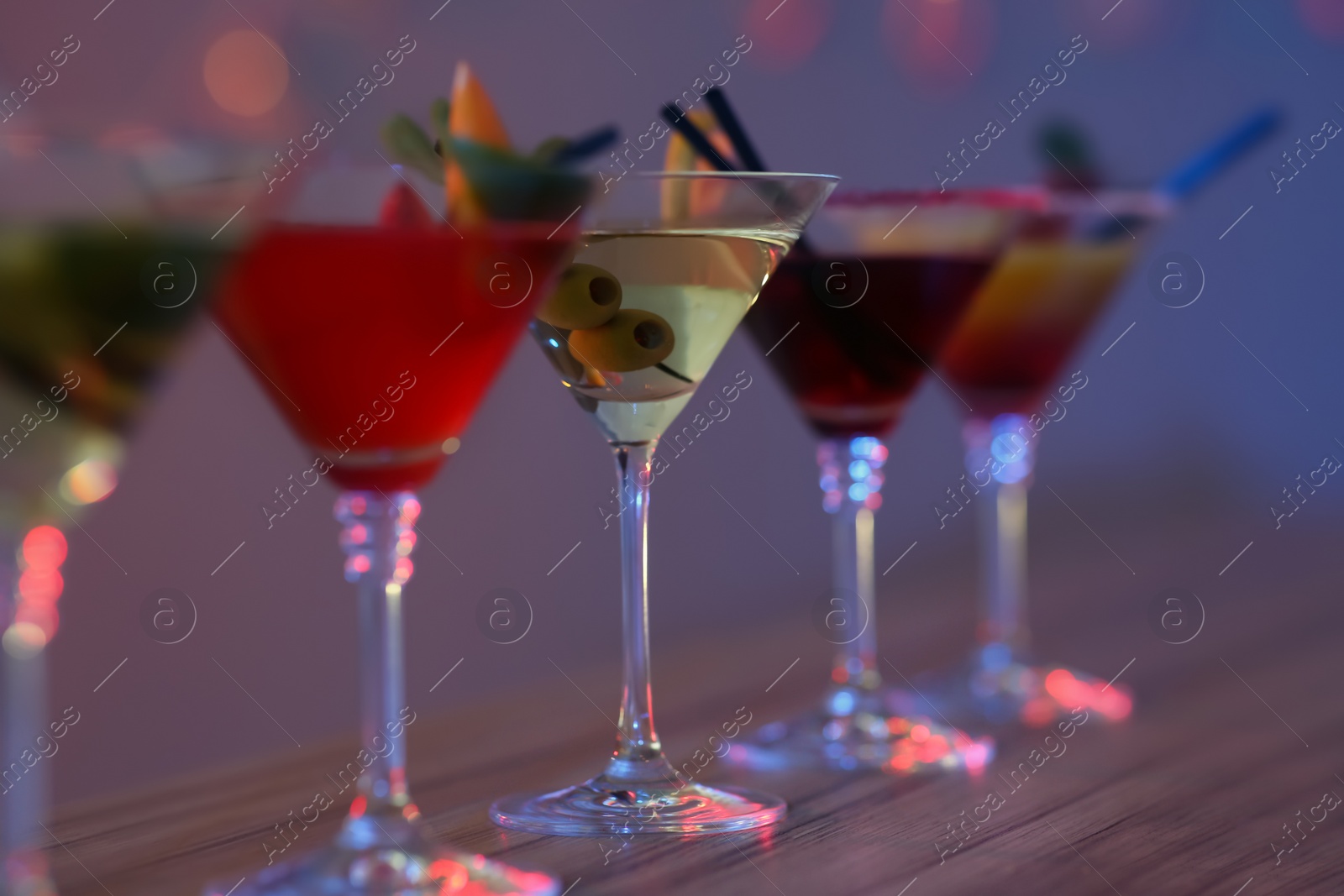 Photo of Different martini cocktails on table in bar, closeup