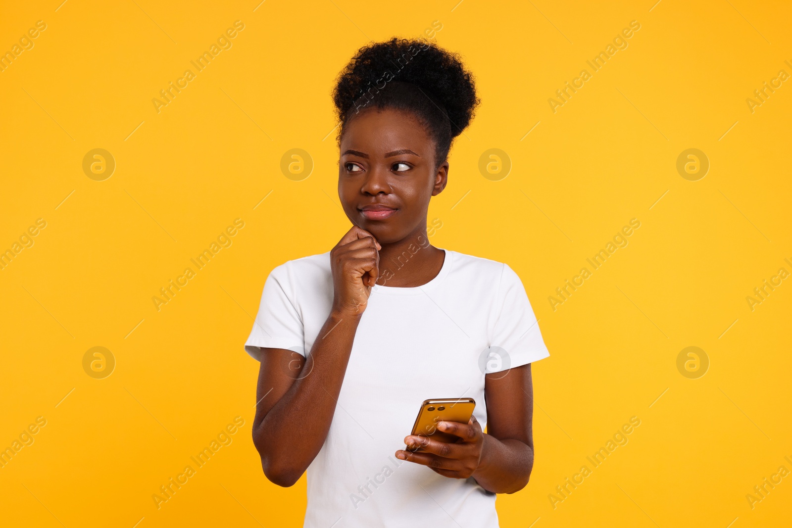Photo of Beautiful young woman with smartphone on orange background
