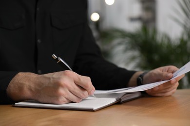 Photo of Man working with document at table in office, closeup