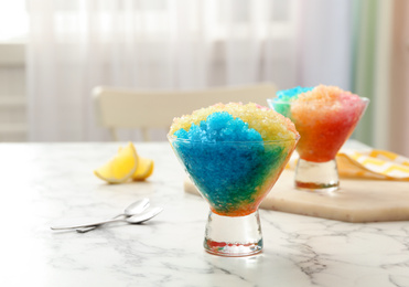 Photo of Rainbow shaving ice in glass dessert bowls on white marble table indoors