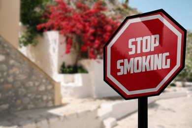 Image of Sign Stop Smoking on city street, space for text