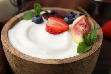 Bowl with yogurt, berries, fruits and mint on table, closeup