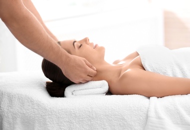 Relaxed woman receiving neck massage in wellness center