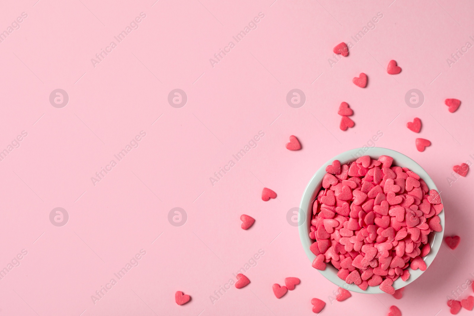 Photo of Heart shaped sprinkles on pink background, flat lay. Space for text