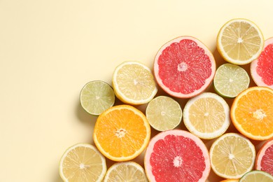 Photo of Different cut citrus fruits on beige table, flat lay. Space for text