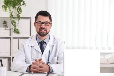 Portrait of male doctor in white coat at workplace