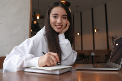 Photo of Young blogger working with laptop in cafe