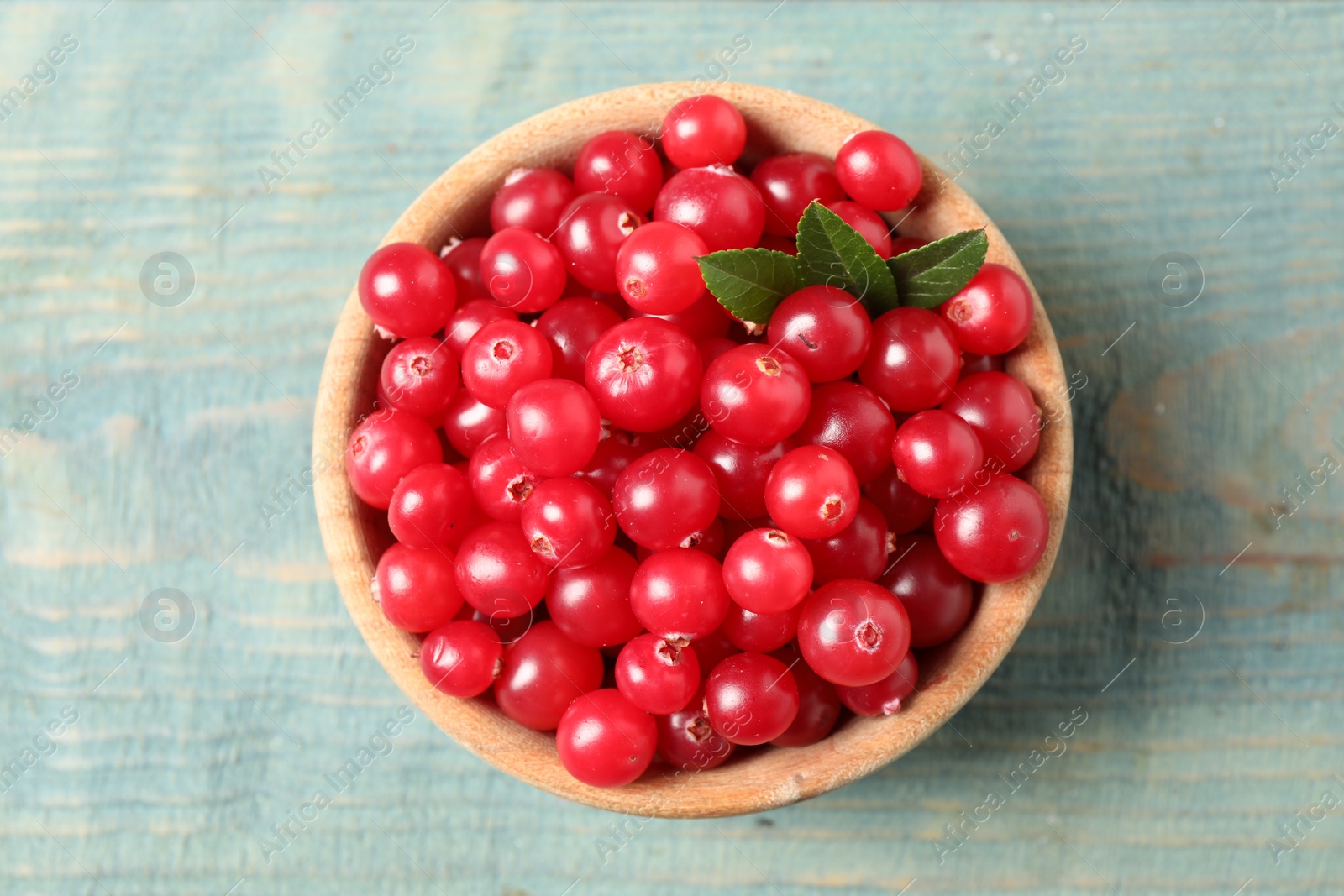 Photo of Tasty ripe cranberries on light blue wooden table, top view