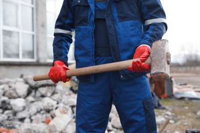 Man in uniform with sledgehammer outdoors, closeup