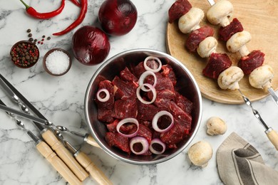 Flat lay composition with metal skewers and bowl of raw meat on white marble table