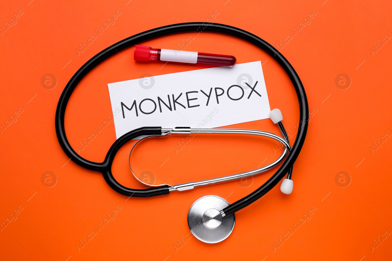 Photo of Word Monkeypox, stethoscope and test tube with blood sample on orange background, flat lay