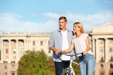 Happy couple with bicycle outdoors on sunny day