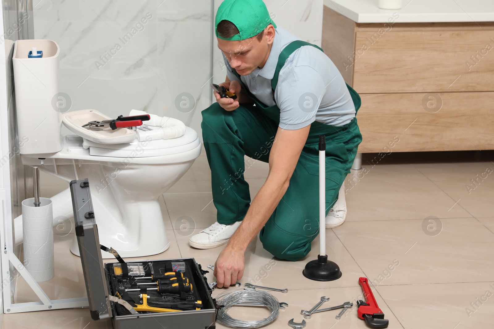 Photo of Professional plumber repairing toilet tank in bathroom