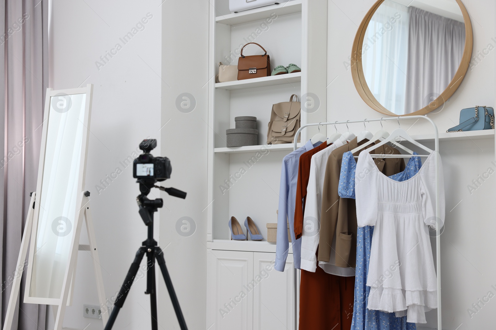 Photo of Fashion blogger's workplace. Shoes, clothes, camera and stylish furniture indoors