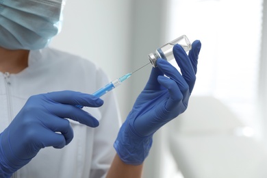 Doctor filling syringe with medication in clinic, closeup. Vaccination and immunization