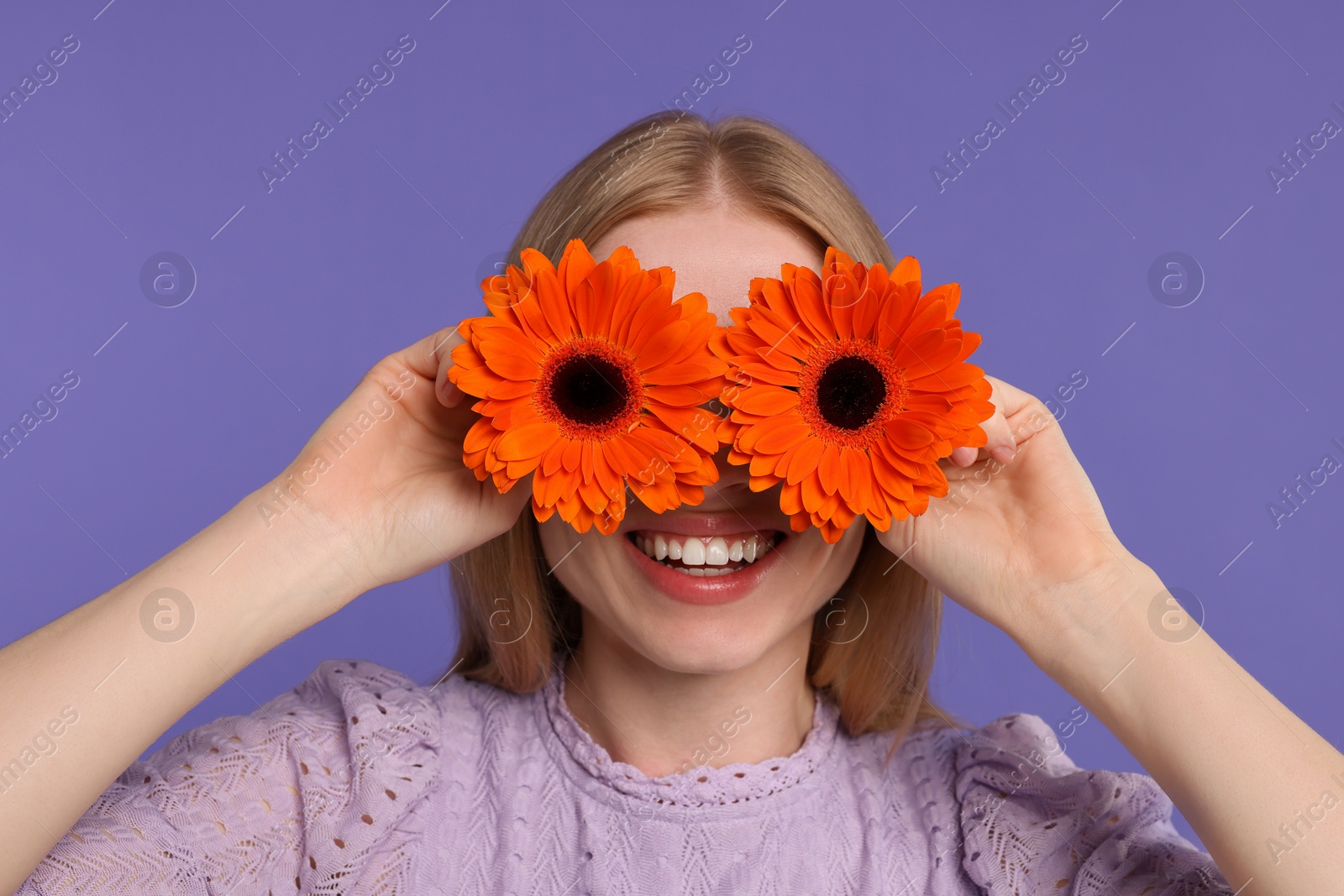 Photo of Woman covering her eyes with spring flowers on purple background