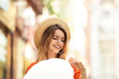 Happy young woman with cotton candy outdoors