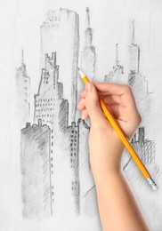 Image of Woman drawing sketch of cityscape with graphite pencil on white paper, closeup