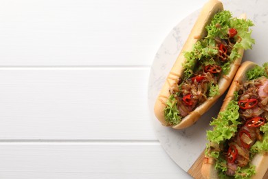 Photo of Tasty hot dogs with chili, lettuce and sauce on white wooden table, top view. Space for text