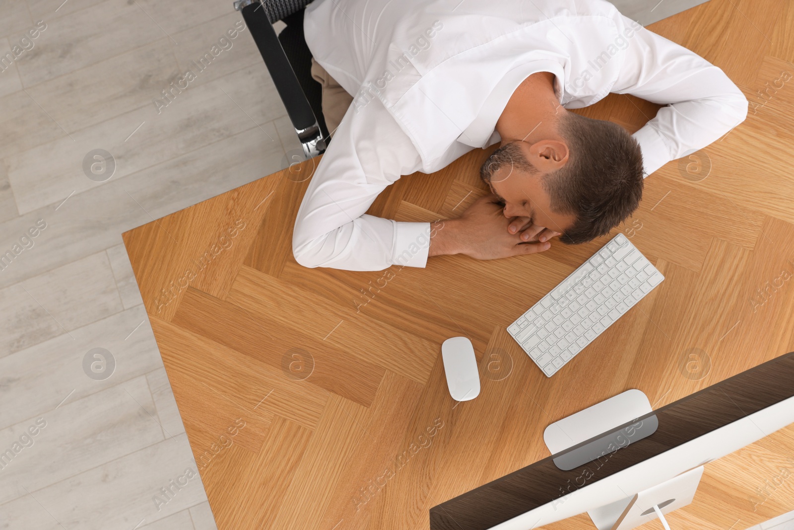 Photo of Tired man sleeping at workplace, top view