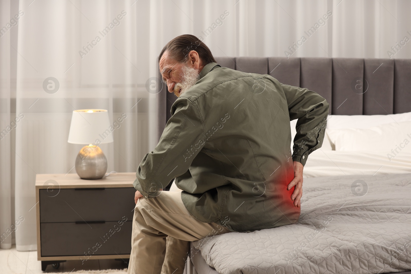 Image of Senior man suffering from pain in lower back on bed at home