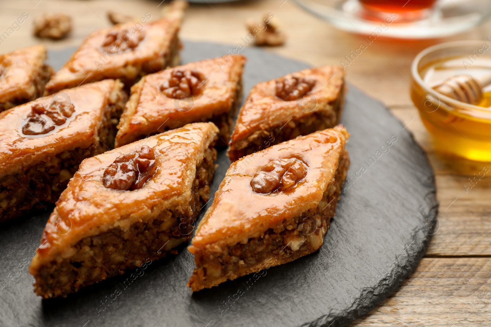 Photo of Delicious honey baklava with walnuts served on wooden table, closeup