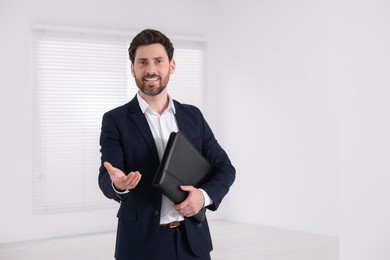 Happy real estate agent with leather portfolio indoors. Space for text