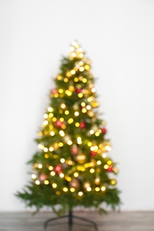 Blurred view of beautiful Christmas tree with fairy lights, indoors