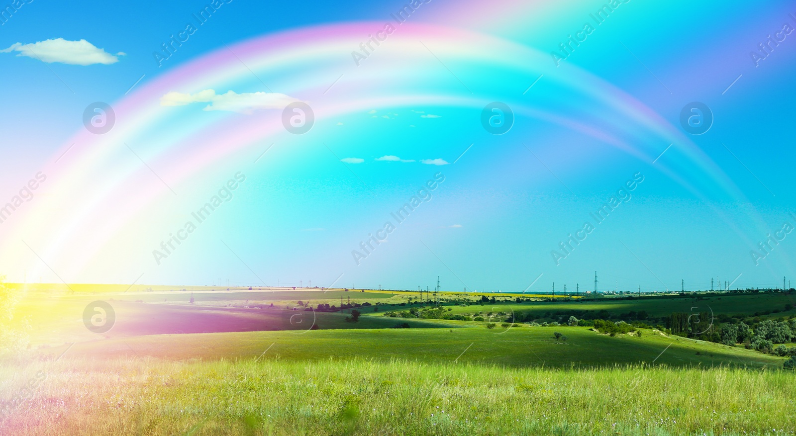 Image of Picturesque view of green meadow and beautiful rainbow in blue sky on sunny day