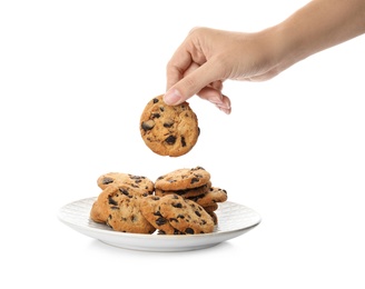 Photo of Woman holding tasty chocolate chip cookie over plate on white background, closeup