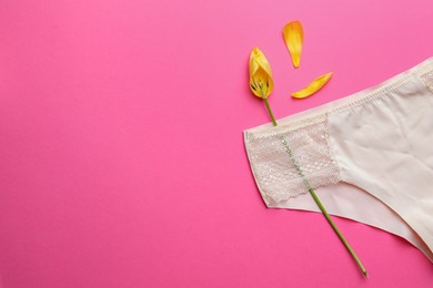 Photo of Yellow tulip and panties on pink background, top view with space for text. Menopause concept