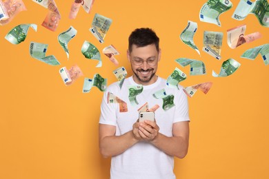 Image of Online payment. Man buying something using mobile phone on orange background. Euro banknotes flying out of gadget demonstrating process of money transaction