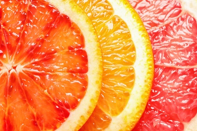 Photo of Slices of fresh citrus fruits as background, top view