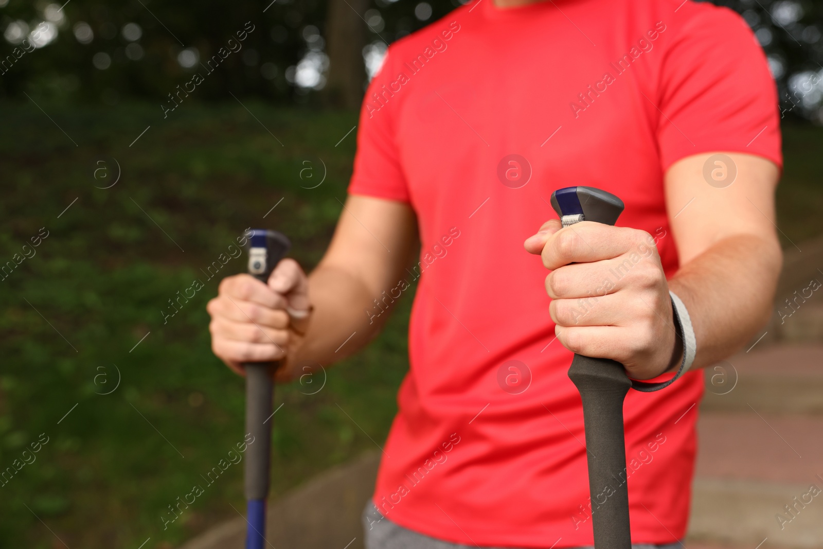 Photo of Man practicing Nordic walking with poles outdoors, closeup