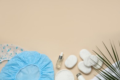 Flat lay composition with shower caps and toiletries on beige background. Space for text