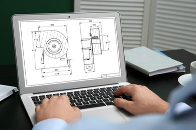 Male engineer working with technical drawing on laptop indoors, closeup