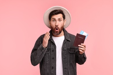 Photo of Surprised man with passport and tickets on pink background